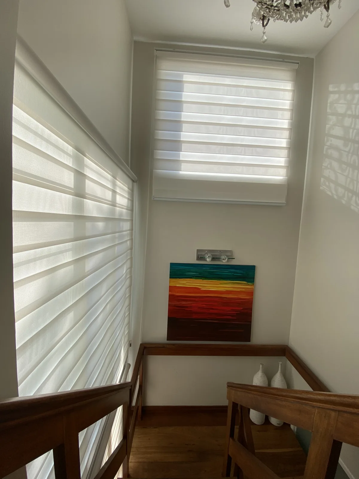 Cortinas romanas claras instaladas em uma abertura junto à escada