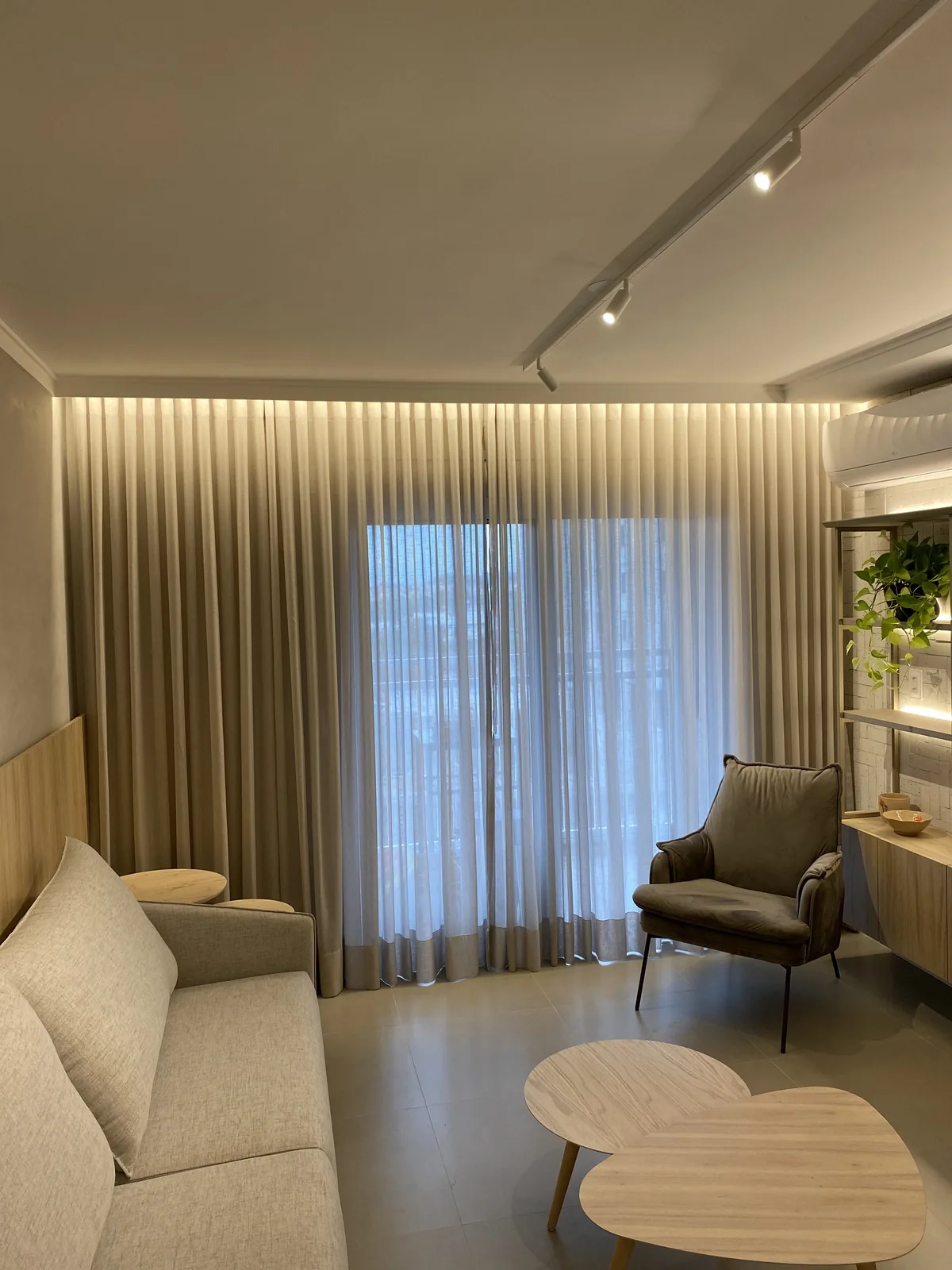 Living de apartamento com cortina de tecido e iluminação indireta